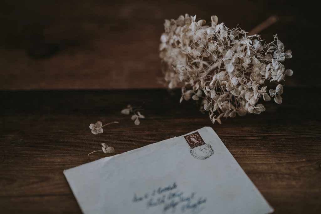 A handwritten pen pal letter lies unopened on the table next to flowers.