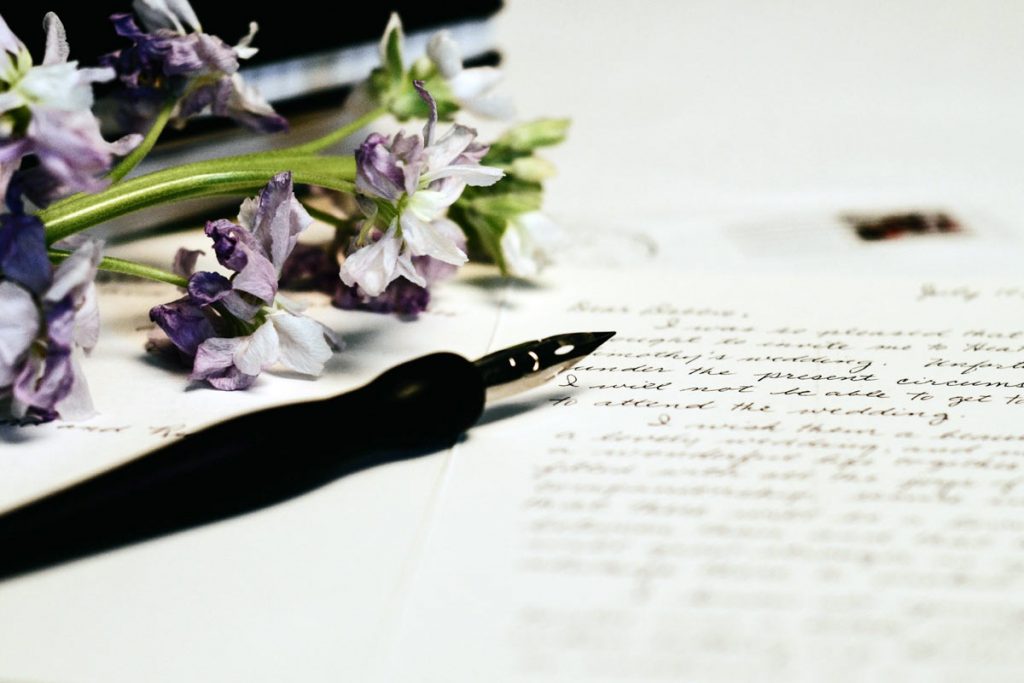 An ink pen lying on paper with flowers on it.