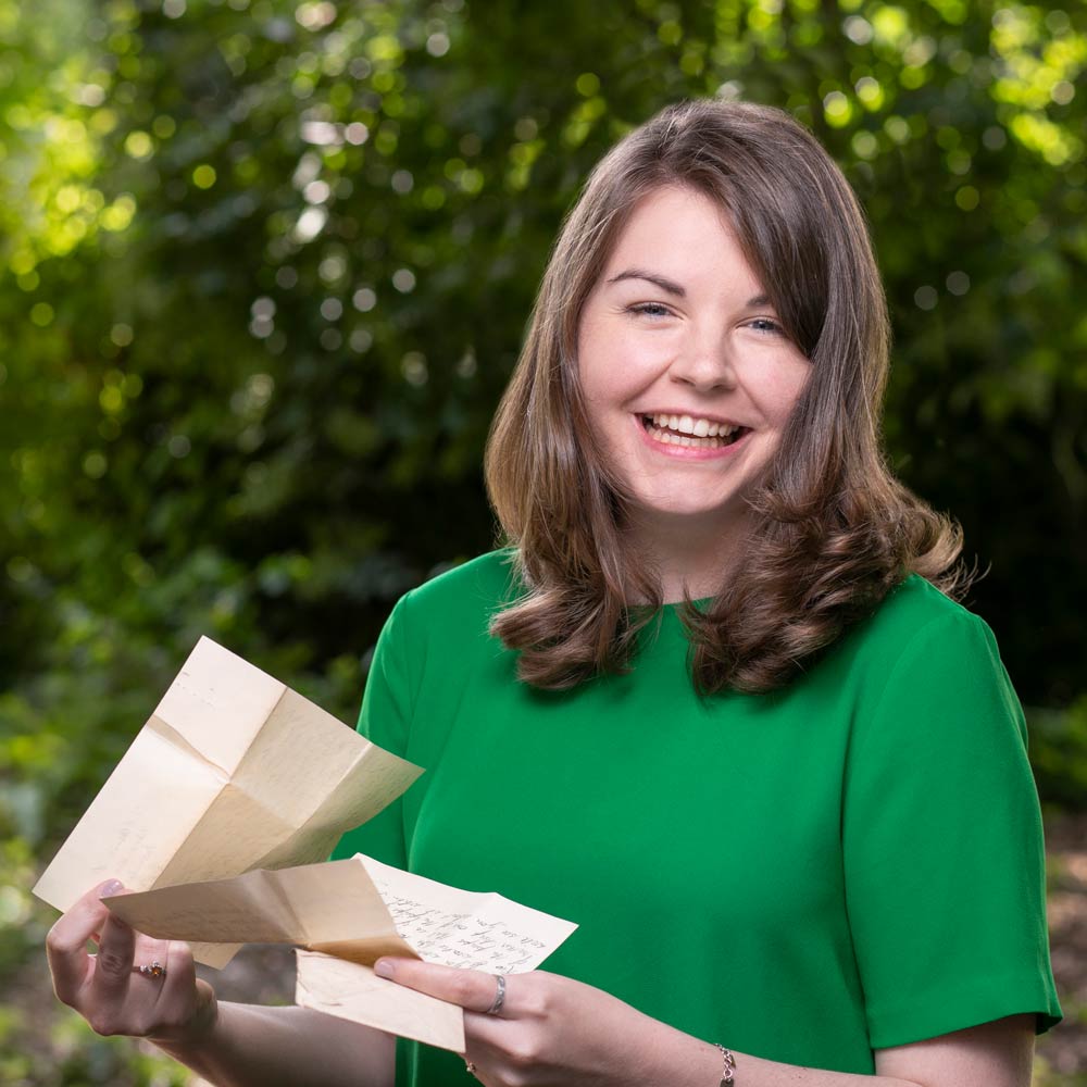 Picture of Liz Maguire holding vintage letters and smiling into the camera