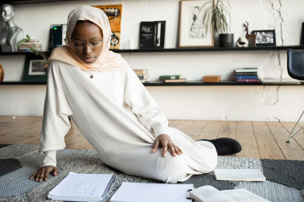 A woman sitting on the floor with language exchange documents from her pen pal surrounding her.