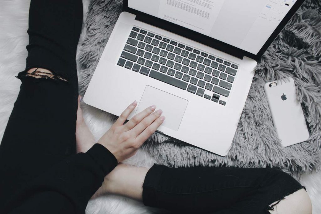 A laptop from above on the carpet with someone writing a letter on it.