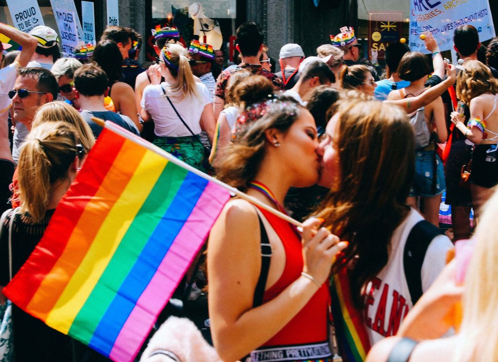 LGBTQ+ pride with two girls kissing and holding a LGBTQ+ flag