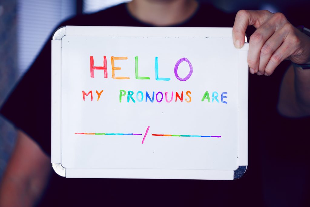 LGBTQ+ pen pal holding a sign with "hello my pronouns are"