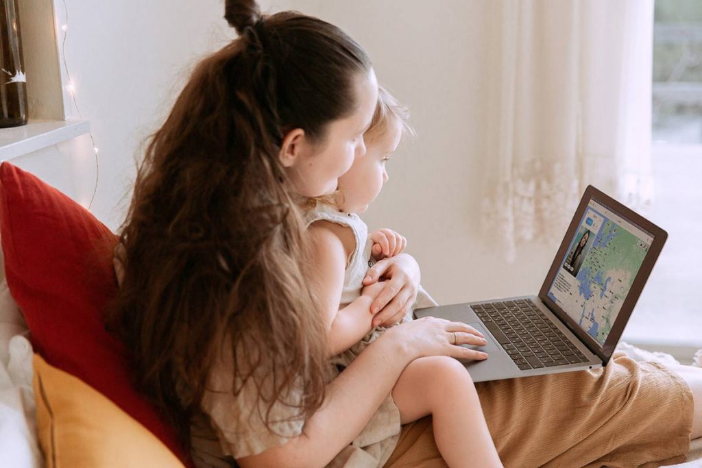 A woman on a laptop with a baby on the knee using PenPal platform