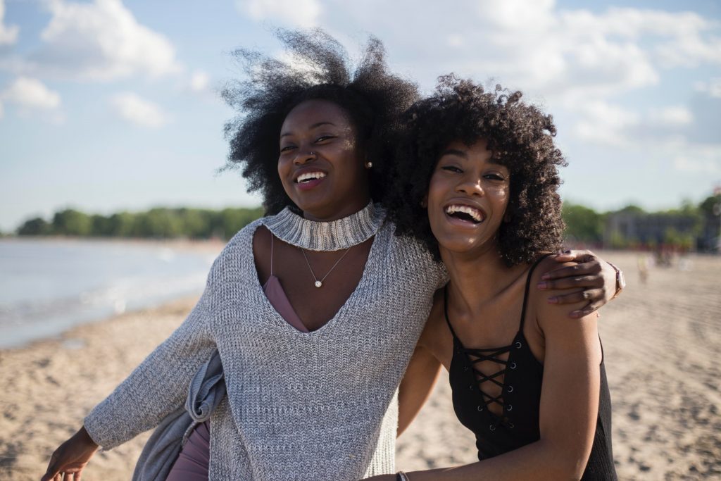 two girls at the beach holding each other in the arms and laughing