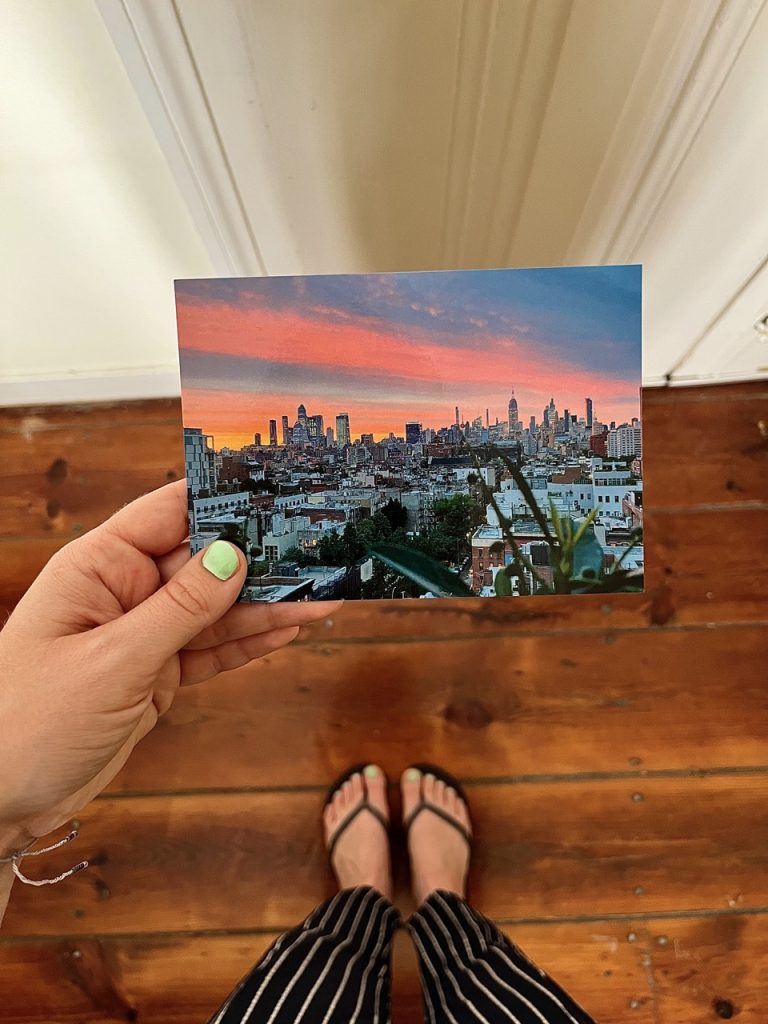 A person is holding a postcard from her pen pal in New York in her hand